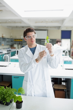 Student holding up beaker with seedling in it in the laboratoryの写真素材