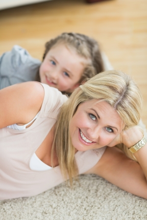 Mother and daughter resting on floor of living roomの写真素材