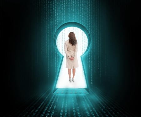 Businesswoman standing in keyhole door in blue and black matrixの写真素材