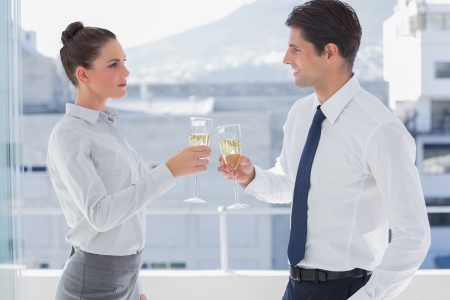 Serious business people clinking their flutes of champagne in a modern officeの写真素材