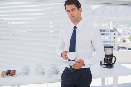 Businessman having a coffee during the break with cupcakesの写真素材