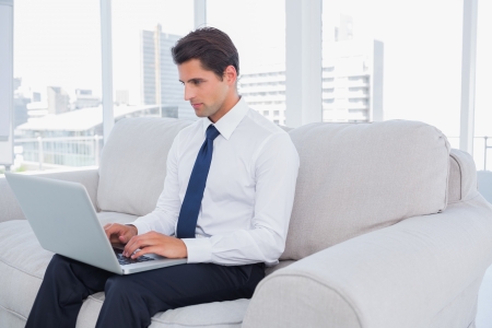 Businessman using laptop on a couch at the officeの写真素材