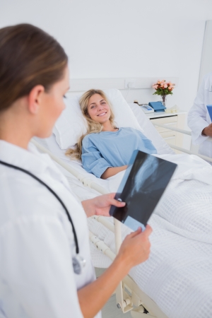 Doctor holding a radiography and standing next to a smiling patientの写真素材