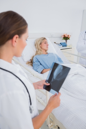 Doctor with radiography standing next to a hospitalized patientの写真素材