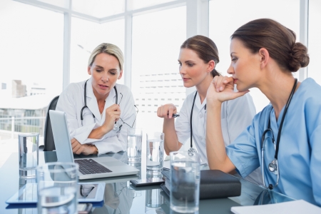 Three women doctors watching a laptop during a meetingの写真素材