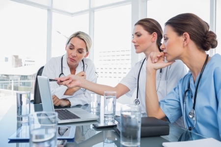 Doctor showing something on a laptop to her colleagues during a meeting roomの写真素材