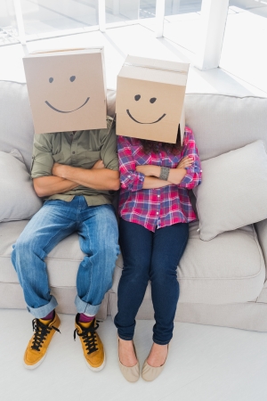 Silly employees wearing boxes on their heads with smiley faces on a couchの写真素材