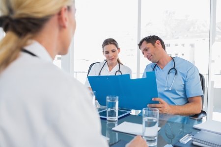 Doctors examining folders in a meeting roomの写真素材