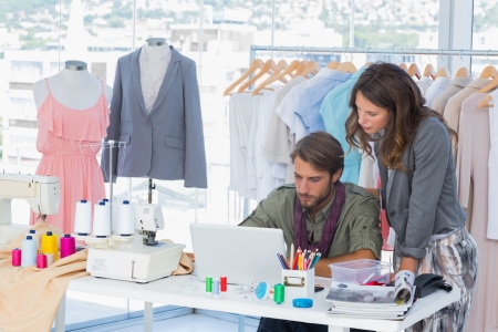 Two fashion designers working on laptop in creative officeの写真素材