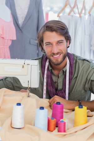 Fashion designer using sewing machine and smiling to the cameraの写真素材
