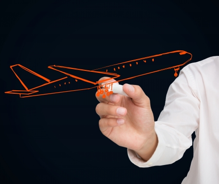 Buisnessman drawing orange airplane on black backgroundの写真素材