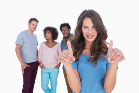 Woman with thumbs standing in front of stylish people against white backgrounの写真素材