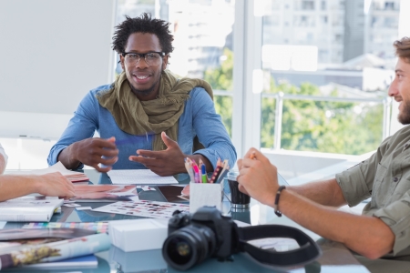 Photo editors brainstorming in bright office at deskの写真素材
