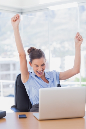 Successful businesswoman cheering in the office の写真素材