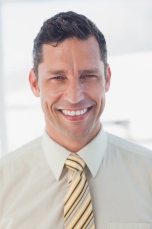 Happy businessman looking at camera in officeの写真素材