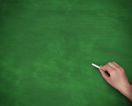 Hand holding chalk on green backgroundの写真素材