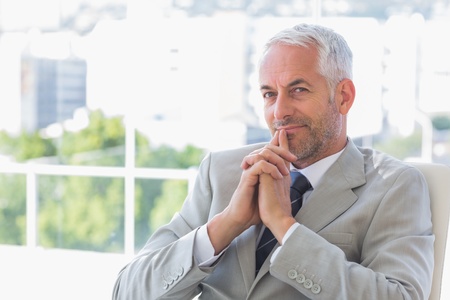 Happy businessman thinking in his officeの写真素材