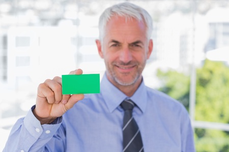 Happy businessman showing green business card in his officeの写真素材