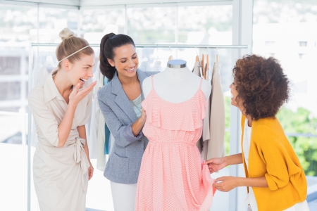 Attractive fashion designers looking at a dress on a mannequinの写真素材