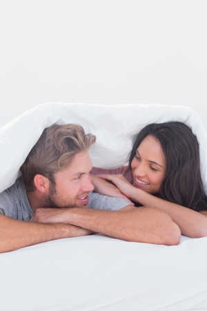 Close couple under the cover in their bedの写真素材