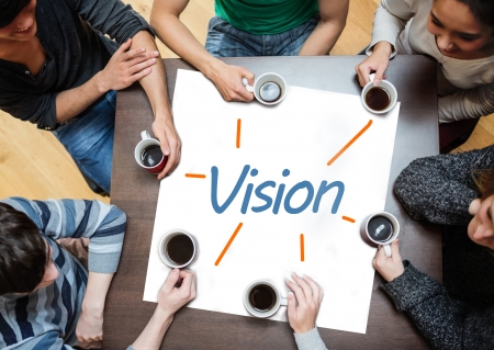 Team brainstorming over a poster on a table with vision written on it