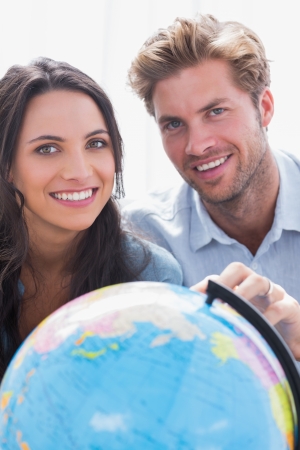 Portrait of a beautiful couple looking together at a globeの写真素材