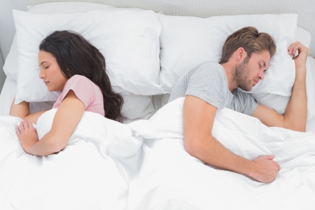 Beautiful couple sleeping back to back in their bed の写真素材
