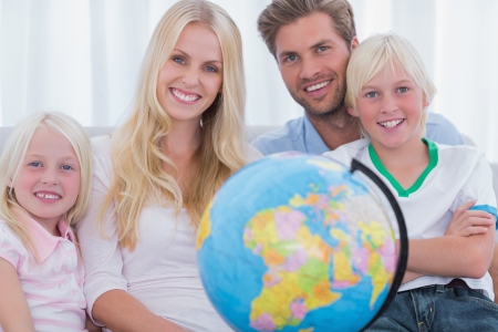 Family sitting on couch holding globe in the living roomの写真素材