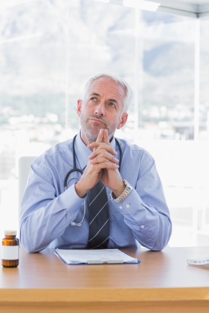 Doubtful doctor sitting behind his deskの写真素材