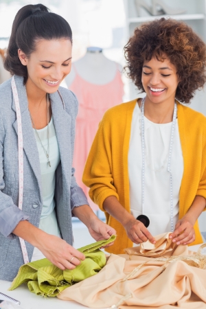 Cheerful fashion designers touching textile in a creative officeの写真素材