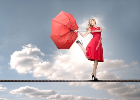 Beautiful woman standing on rope with the sky in backgroundの写真素材