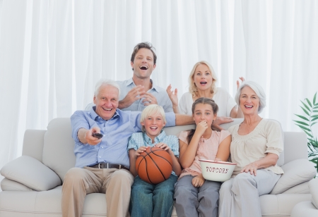 Extended family watching the television on couchの写真素材