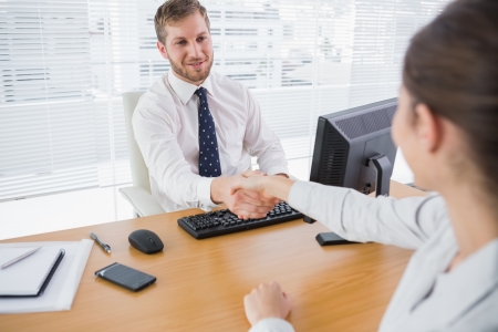 Businessman shaking hands with a colleague at his desk in the officeの写真素材