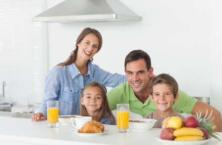 Portrait of cute family having breakfast at home in kitchenの写真素材