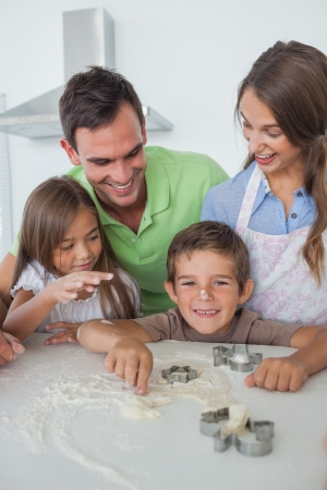Brother with flour on the nose baking with his family in the kitchenの写真素材