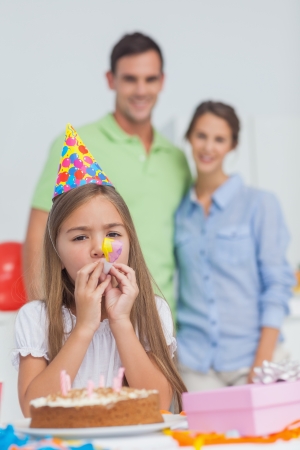 Little girl playing with a party horn during her birthdayの写真素材
