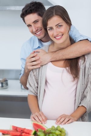Man embracing his pregnant wife in the kitchenの写真素材