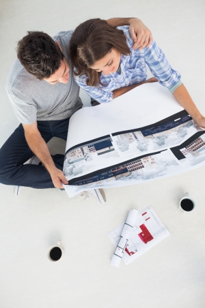 Overview of a man and his wife holding house plan in their new house