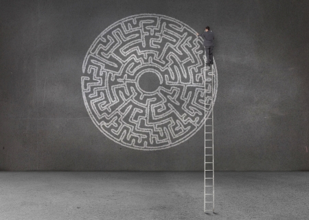Businessman drawing a labyrinth in an empty dark roomの写真素材