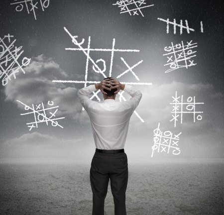 Anxious businessman losing at noughts and crosses with hands on headの写真素材