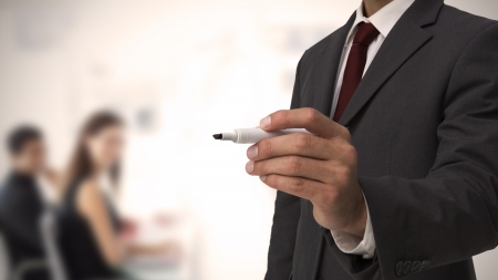 Businessman holding a marker in front of business teamの写真素材