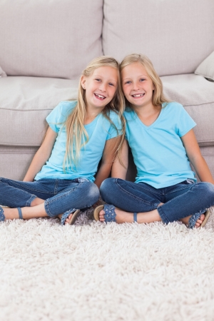 Young twins sitting on a carpet in the living roomの写真素材