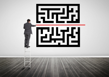 Businessman standing on a ladder drawing red line through qr code in empty roomの写真素材