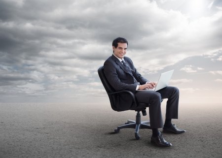 Handsome businessman sitting on a swivel chair and using his laptopの写真素材