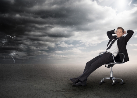 Businessman sitting in a swivel chair outside during a stormy weatherの写真素材