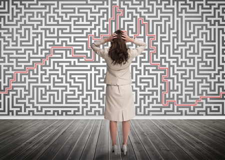 Puzzled businesswoman looking at a maze on a wallの写真素材