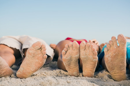 Picture of friends feet lying together on the beachの写真素材