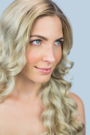 Thoughtful natural blonde posing on grey backgroundの写真素材