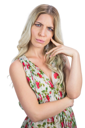 Frowning pretty blonde wearing flowered dress posing on white backgroundの写真素材