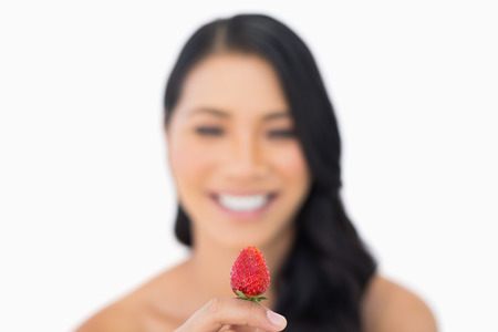 Attractive brown haired model holding strawberry on white backgroundの写真素材